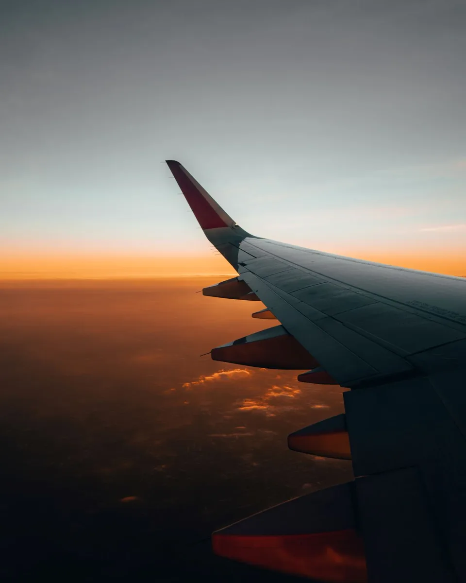 Airplane wing over sunset clouds